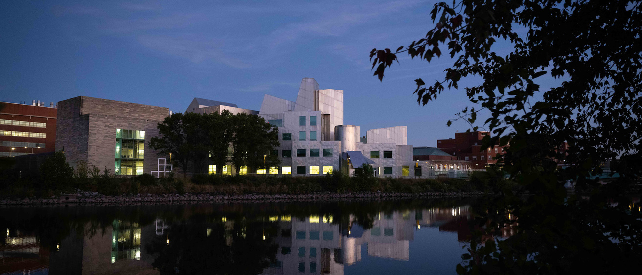 The Iowa Advanced Technology Laboratories Building from across the river at dusk. The building is reflected in the river's waters below.