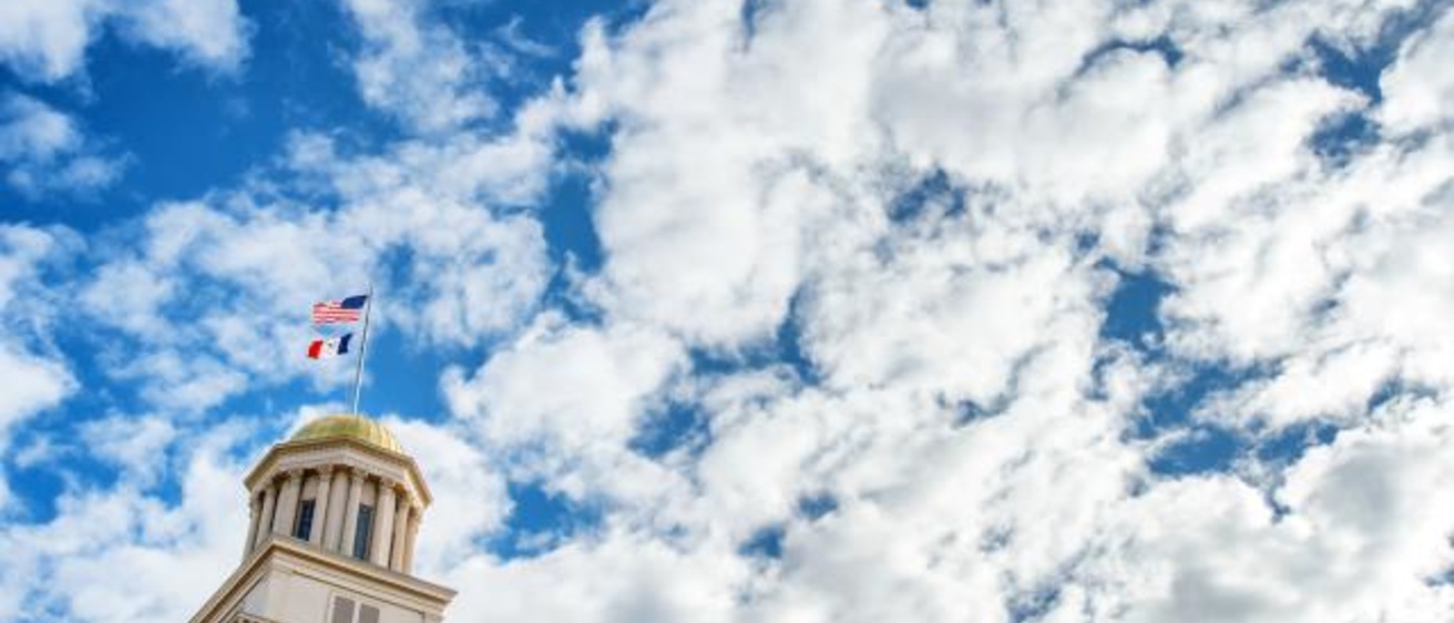 The top of the Old Capitol building photographed against a blue and white cloud sky