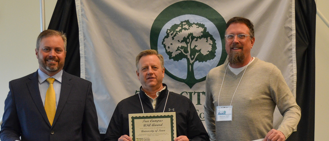 Members of Landscape Services hold up a Tree Campus USA and certificate celebrating their status as UI's Tree Campus Higher Education