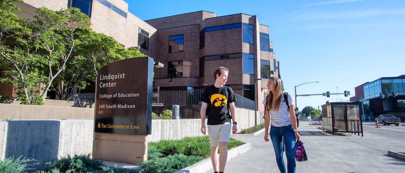 Two students walk past the west side of the Lindquist Center along Madison Street.