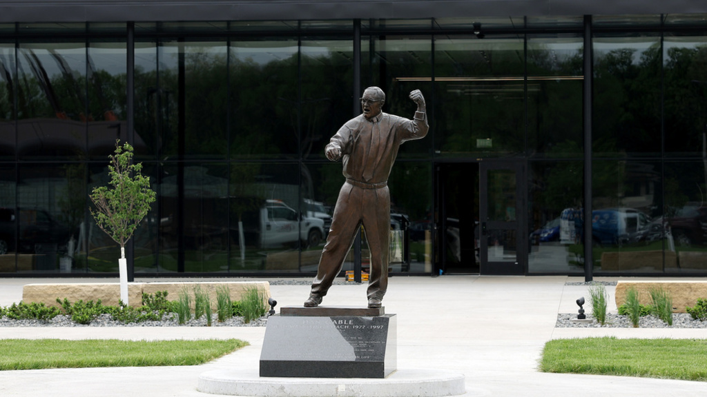 Picture of the outside of the new wrestling training factuality. You see all of the glass windows and a statue of Dan Gable. 